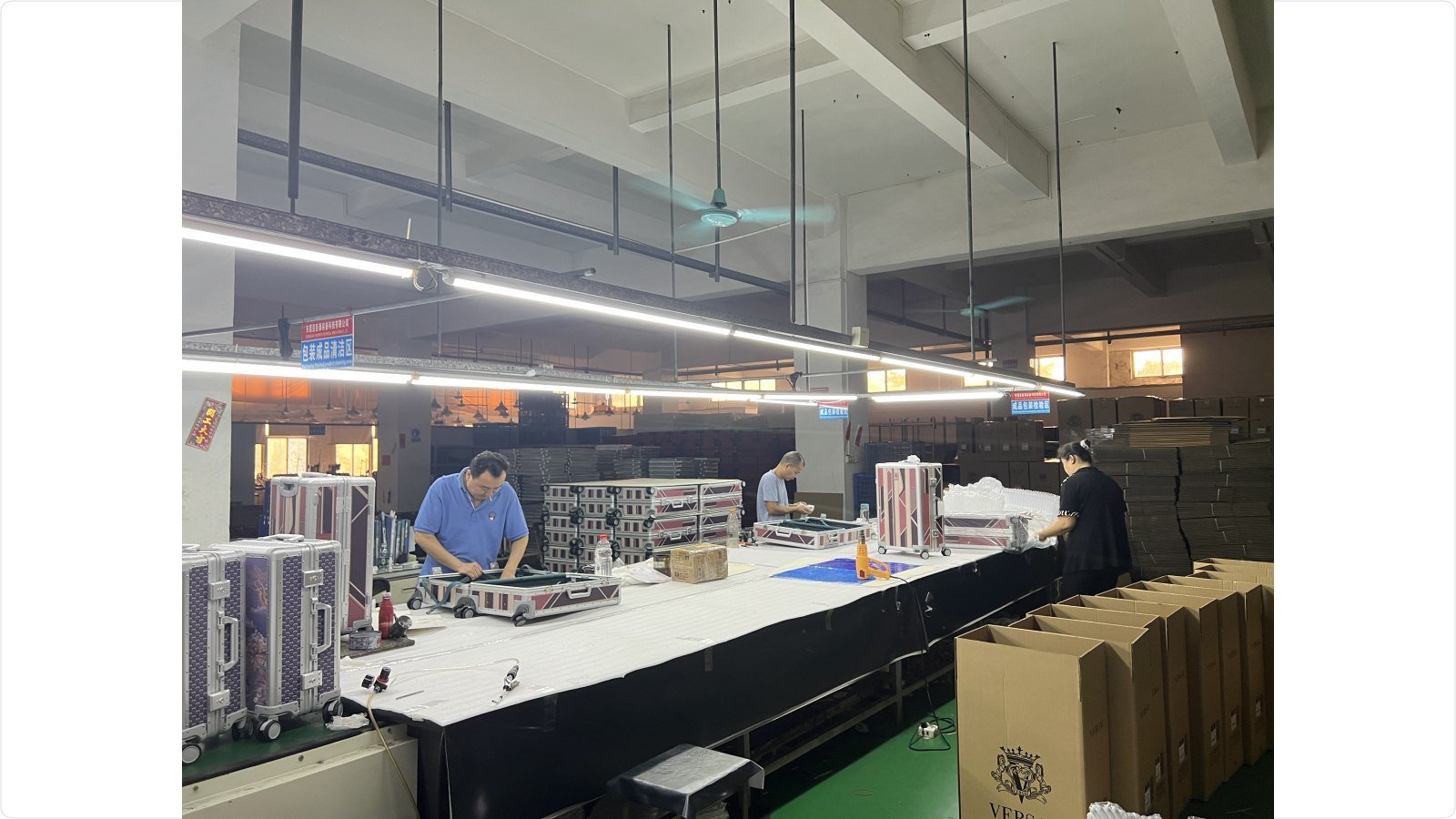 Open luggage cases and workers at an interior fitting and packing workbench