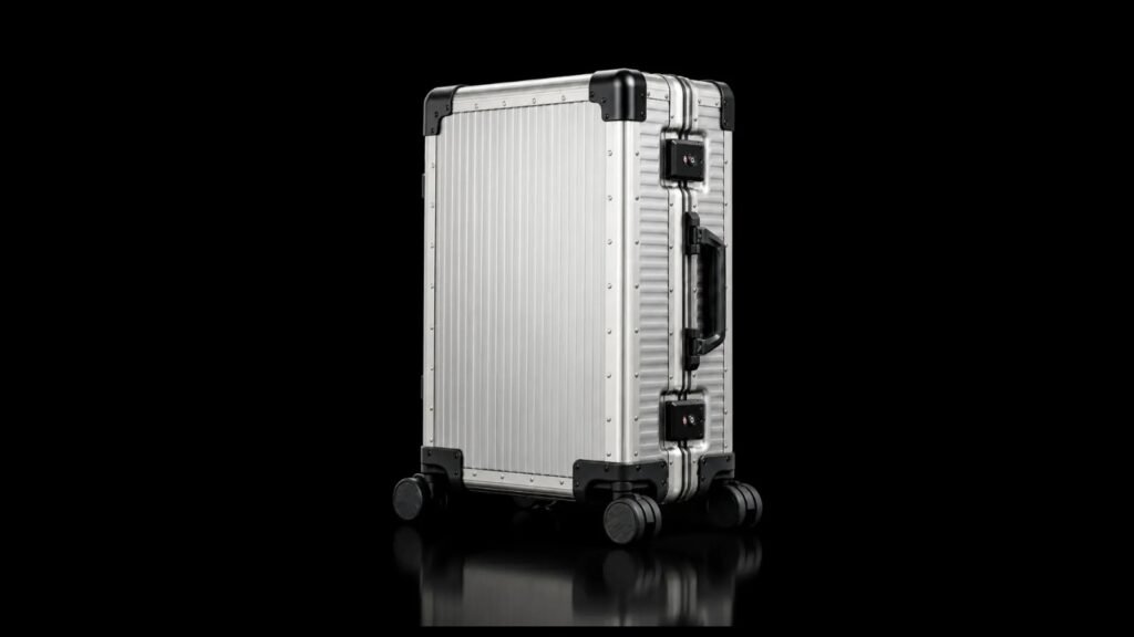 Silver TT-001 suitcase with black corner guards and spinner wheels